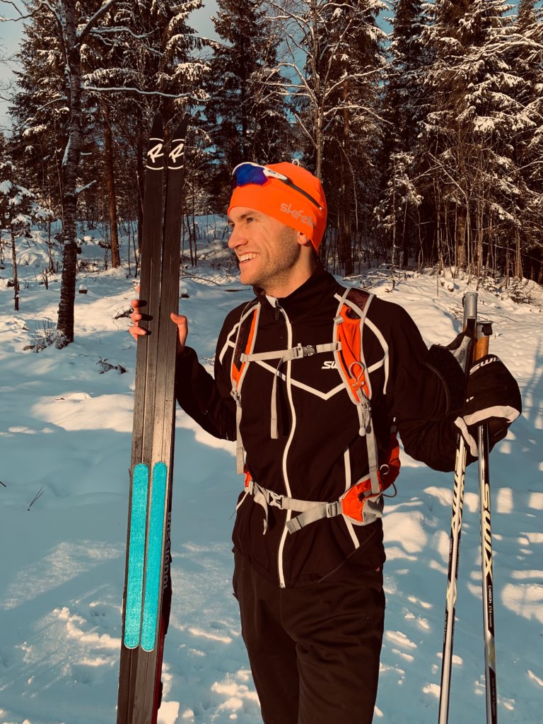 Glad skiløper med på omgjorte felleski i skogen. Viser frem Skifellas skifeller.